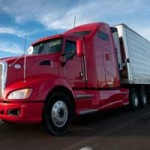 Red semi pulling white trailer. Learn how to become a truck driver.