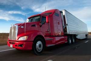 Red semi pulling white trailer. Learn how to become a truck driver.
