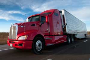 Red semi pulling white trailer. Learn how to become a truck driver.