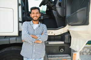 A truck driver standing outside his truck.